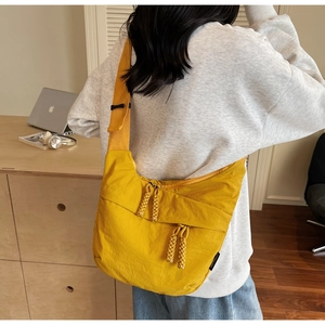 Detail of a bright yellow nylon crescent crossbody bag with woven zipper pullers