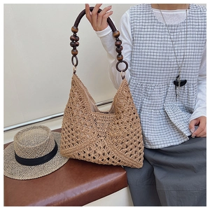 Detail of woven straw tote bag with unique dark brown wooden bead handles and hollow crochet