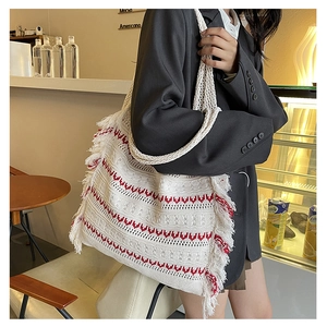 Detailed knit tote bag with red geometric waves and white fringe in a cafe setting