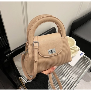 Detail of beige pleated handbag featuring silver twist lock and smooth leather flap cover