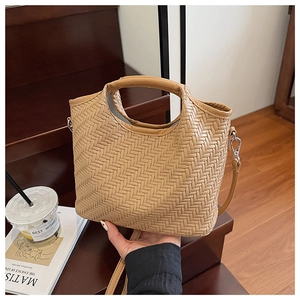 Detail of woven texture on a tan crossbody bucket bag featuring a round handle and strap