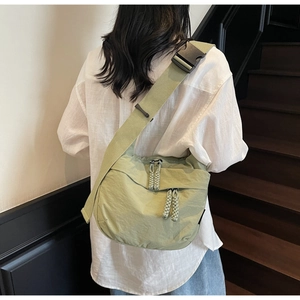 Detail view of light green crossbody bag with adjustable wide strap and buckle on a model