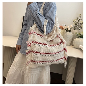 Detail of bohemian knitted tote bag with red wave patterns and fringe decorative edges