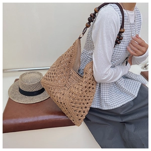 Detail of hand-woven hollow geometric pattern and brown wooden bead shoulder strap on tote