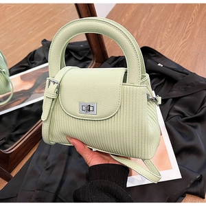 Close-up of mint green pleated handbag with silver twist lock and lychee leather texture