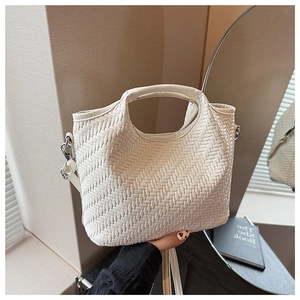 Detail of off-white woven tote bag with metallic buckles and adjustable shoulder strap