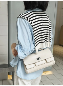 Detail of cream white leather handbag featuring silver square lock and double front flaps