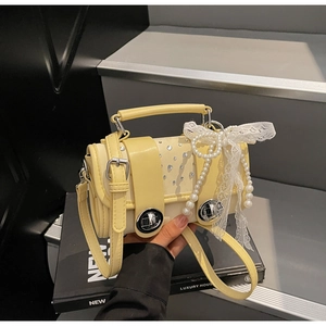 Detail of yellow woven mini crossbody bag with pearl chain and lace bow decoration