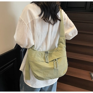 Detail showing avocado green nylon crescent bag with woven beige rope zipper pullers