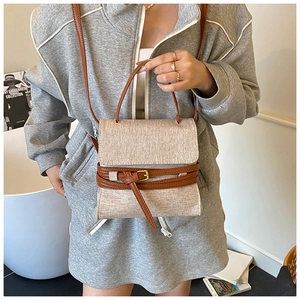 Détail d'un sac en toile beige avec bandoulière en cuir marron et boucle dorée