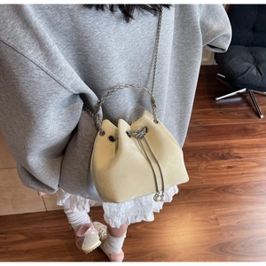 Detail of beige bucket bag featuring silver butterfly charms and chain strap