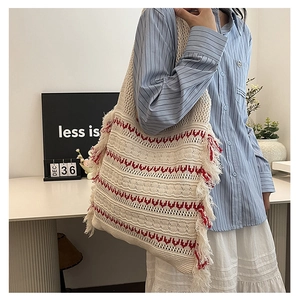Detail of bohemian knit tote bag with red geometric patterns and long side fringes