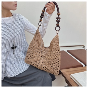 Detailed macro view of woven straw tote bag with round brown wooden bead shoulder strap