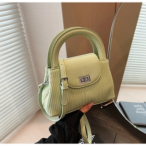 Detail of light green quilted crossbody bag with silver twist lock and ribbed leather texture