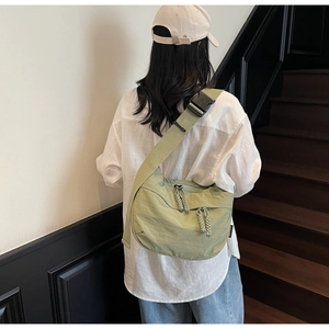 Detail of light green nylon crescent crossbody bag with adjustable strap and buckles