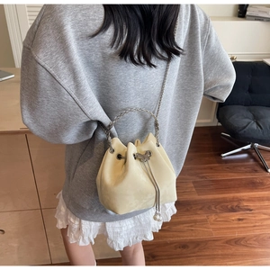 Detail of cream drawstring bucket bag with silver butterfly charm and pearl accents