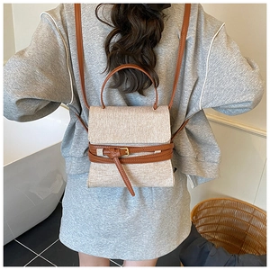 Détail d'un sac à dos chic en toile beige et cuir marron porté par un mannequin
