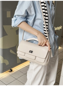 Detail of cream leather flap bag featuring silver twist-lock and slim shoulder strap