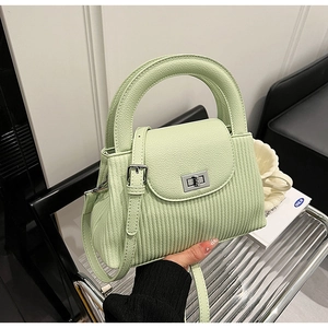 Detail view of light green pleated handbag featuring silver metal twist-lock and textured finish