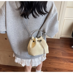 Creamy leather bucket bag with chain strap and pearl charm detail shown on model