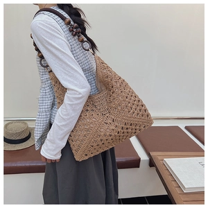 Detail of hand-woven straw tote with hollow diamond pattern and wooden bead shoulder strap