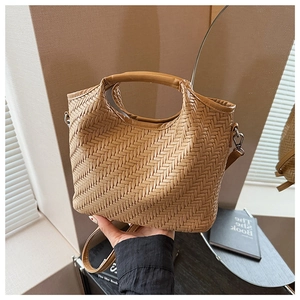 Detail of a brown woven crossbody bag with integrated handle and adjustable strap