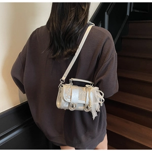 Silver woven crossbody bag with pearl chain and lace bow detail on a shoulder model