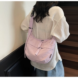 Close-up of light purple crescent nylon bag with adjustable wide strap and woven zipper