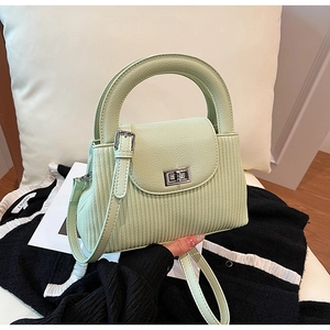 Detail of light green faux leather handbag featuring silver twist lock and pleated side panels
