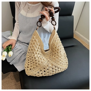 Close-up of beige woven straw tote bag with intricate hollow patterns and wooden bead handles