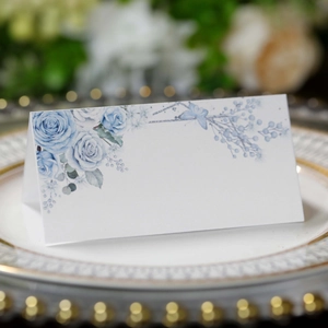 Detailed view of floral wedding place card with blue roses on an elegant plate setting