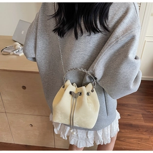 Detail of drawstring bucket bag featuring silver butterfly decor and pearl tassels