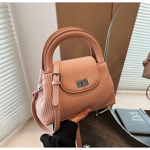 Close-up of pleated salmon pink handbag showing vertical textures and silver metal turn lock