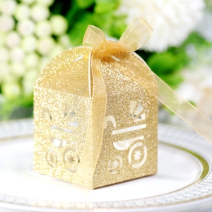 Close-up of golden glitter laser-cut baby carriage candy box with ribbon