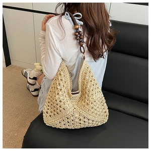 Detail of woven straw shoulder bag featuring decorative dark brown wooden bead straps