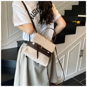 Détail d'un sac bandoulière en toile avec bordure en cuir marron porté par un mannequin