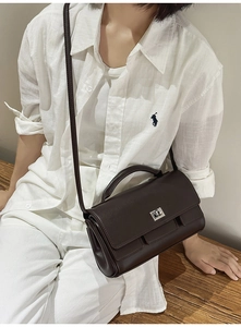 Detail of dark brown leather handbag with silver twist lock and minimalist pleated design