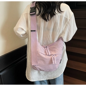 Rear view of a light purple nylon crescent bag on a person wearing white top and denim