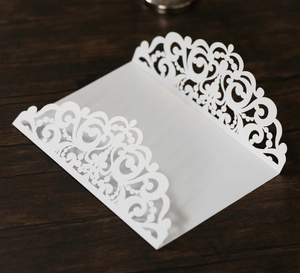 Détail macro d'une invitation de mariage blanche découpée au laser avec motifs de dentelle