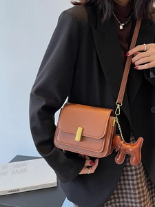 Brown faux leather crossbody bag with gold buckle and a cute dog charm on model