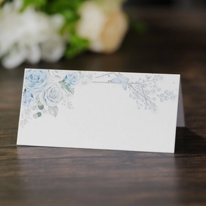 Macro shot of blue floral wedding place card with watercolor roses and laser cut details