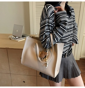 Detail of large beige tote bag in lychee leather featuring Fashion & Lucky print