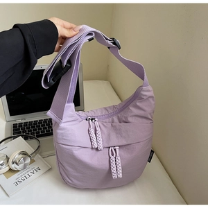 Detail of lavender nylon crescent bag with woven zipper pull on a desktop background