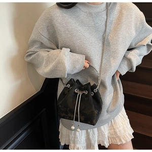 Detail of black velvet bucket bag with silver round handle and pearl drawstring charms
