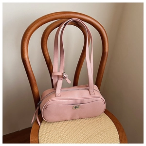Detail der rosa Lederhandtasche mit Kieselmaserung und Metalldrehverschluss auf Stuhl