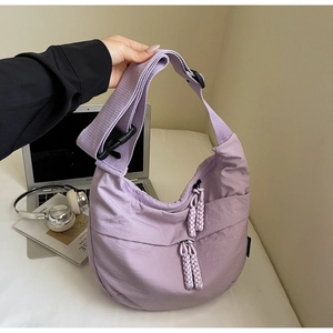 Macro detail of lavender nylon crescent bag featuring woven zipper pulls and adjustable strap