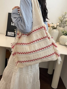 Knitted tote bag with red wave patterns and fringe detail shown in a lifestyle setting