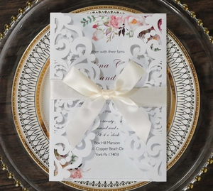 Invitation de mariage découpée au laser avec nœud en soie et carte fleurie sur plateau