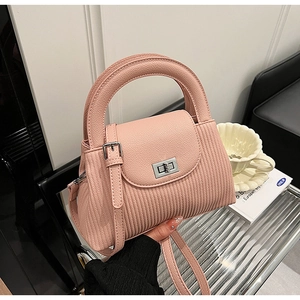 Detail of pink lychee leather handbag with vertical pleats and silver metal twist lock