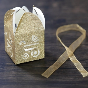 Detail of glitter gold baby carriage laser cut gift box with metallic ribbon and texture